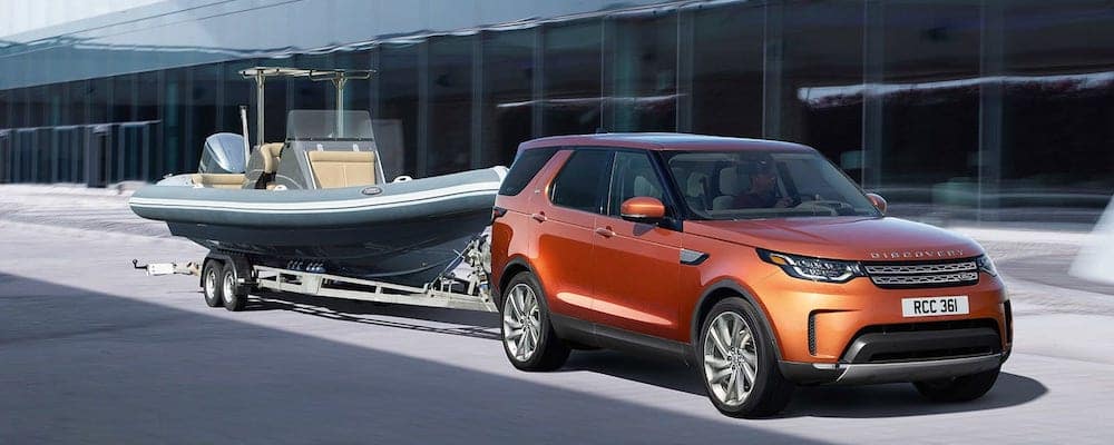 An orange Land Rover Discovery towing a leisure boat on a trailer