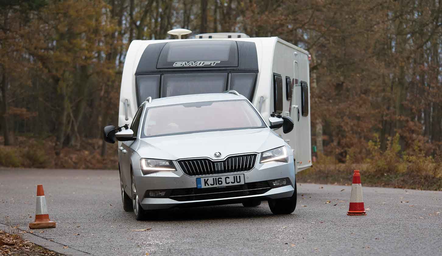 A silver 2016 Skoda Superb towing family caravan on a towing agility course